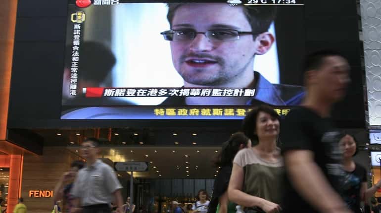 A TV screen shows a news report of Edward Snowden,...