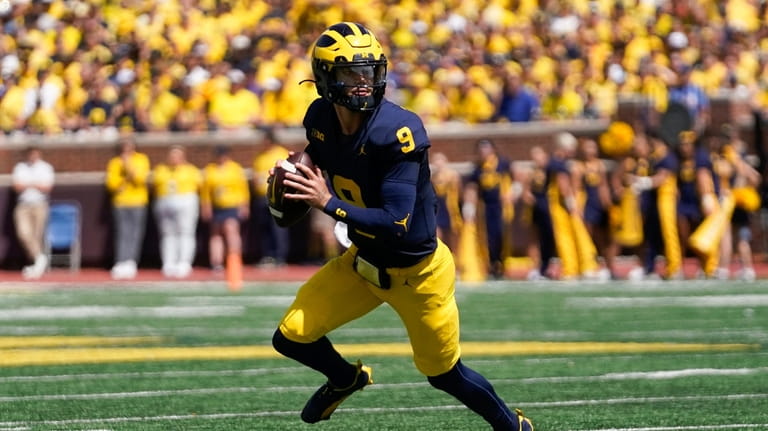 Michigan quarterback J.J. McCarthy rolls out to pass against East...