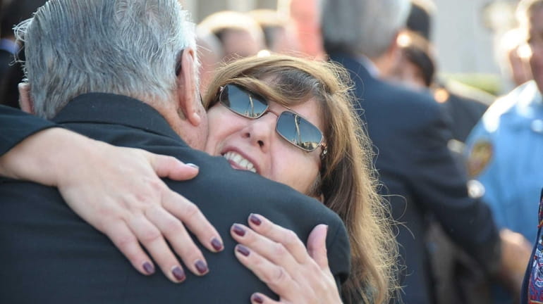 Grieving family and friends embrace after the funeral Mass for...