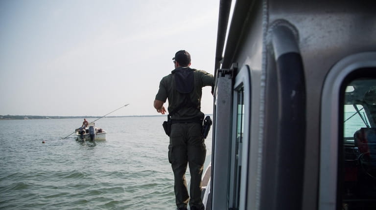 Environmental Conservation Officer Evan Laczi prepares to board a clamming...