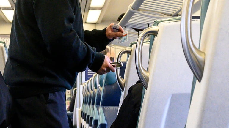 LIRR conductor punches tickets on an eastbound train on the...