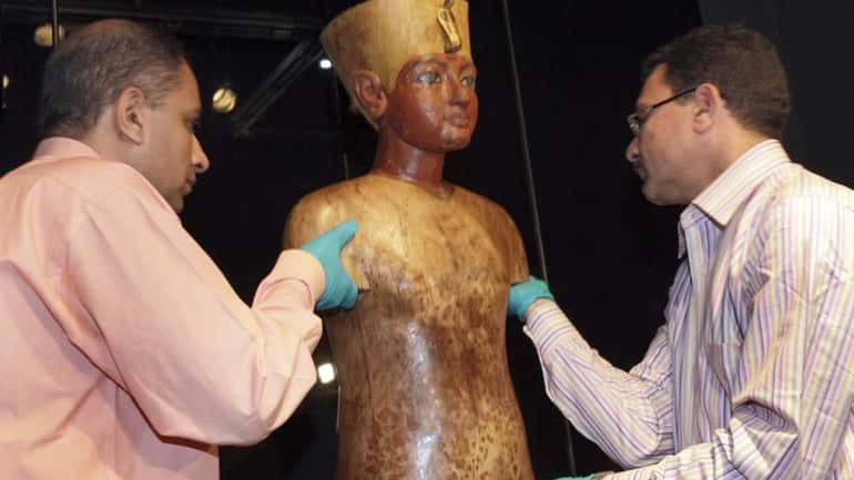The "Torso of Tutankhamun" is installed by Ashtaf Nageh, left,...