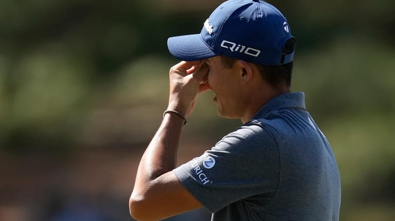Collin Morikawa reacts after missing a putt on the seventh...