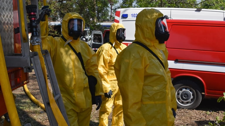 Ukrainian emergency workers wearing radiation protection suits attend training in...