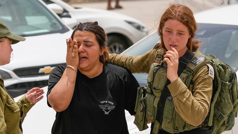 An Israeli soldier cries outside a military base following a...
