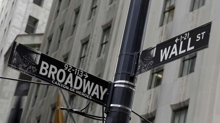 Street signs mark the corner of Broadway and Wall Street,...