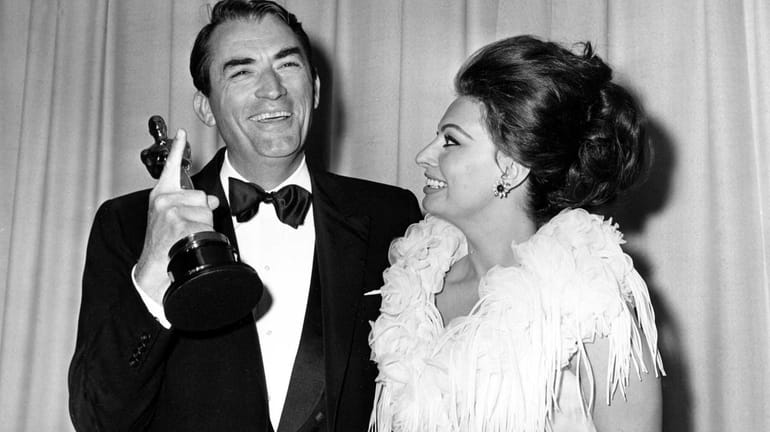 Gregory Peck indicates his one Oscar after winning his first,...