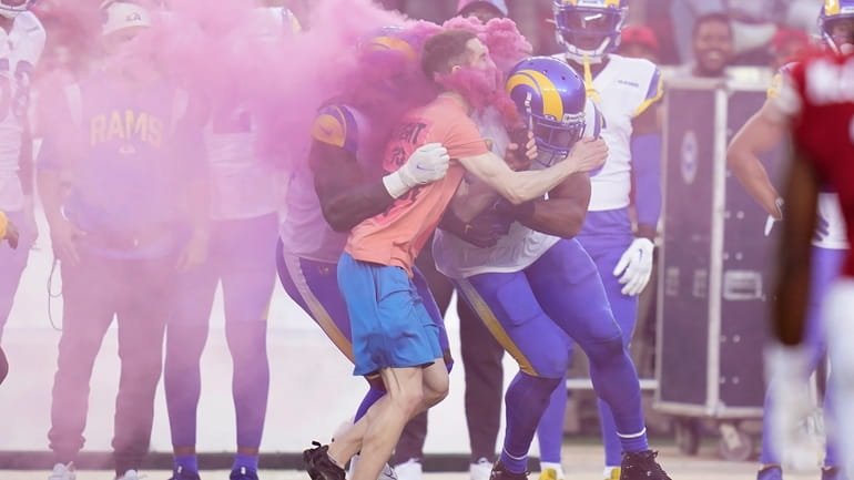 A protester is hit by Los Angeles Rams defensive end...