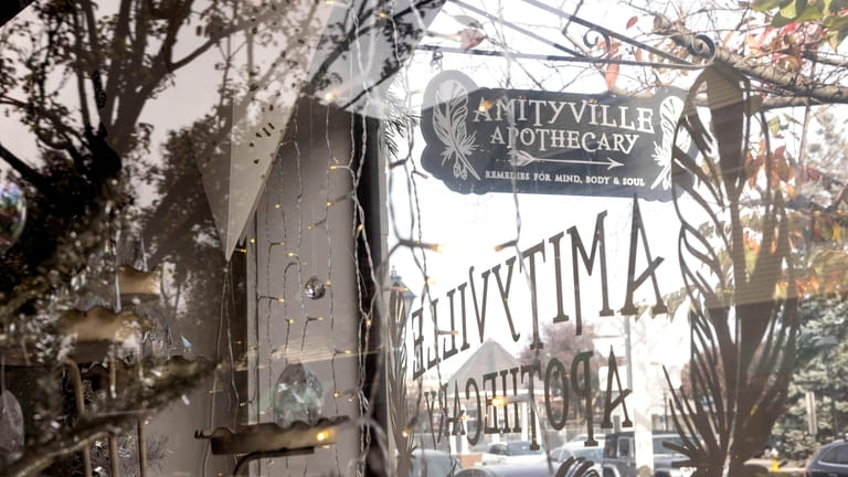 The decorated front window at the Amityville Apothecary, which also...