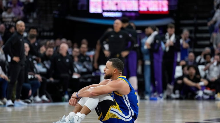 Golden State Warriors guard Stephen Curry sits on the court...