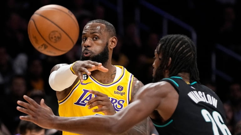 Los Angeles Lakers forward LeBron James, left, passes the ball...