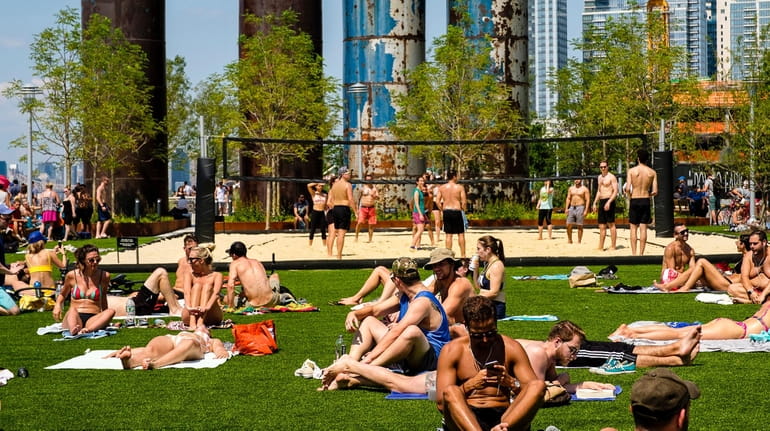 Sunbathers cover the lawn at Domino Park on Kent Avenue...