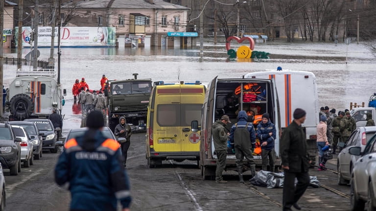 Emergency workers gather near their vehicles during evacuations in a...