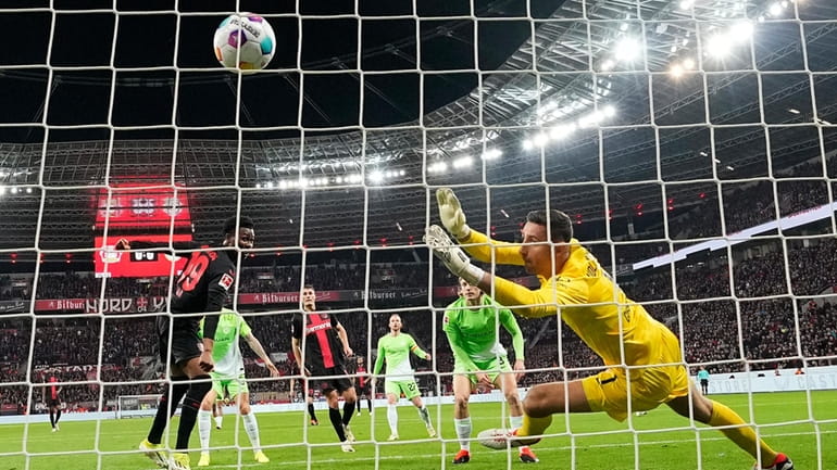 Leverkusen's Nathan Tella, left, scores the opening goal past Wolfsburg's...