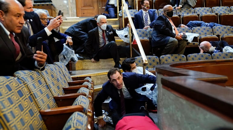 Members of Congress shelter in the House gallery as rioters...