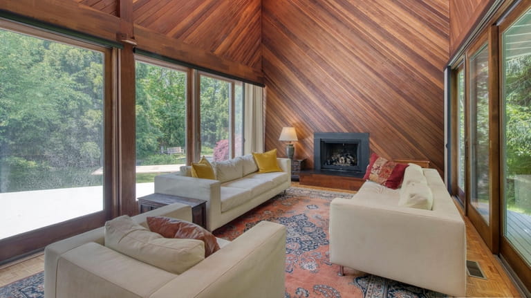 The great room has large windows and redwood paneling, found...