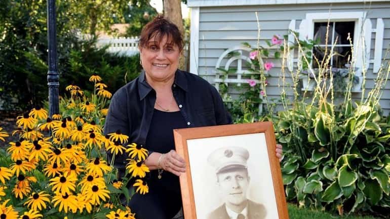 JoAnn Cross displays a portrait of her late husband, firefighter...