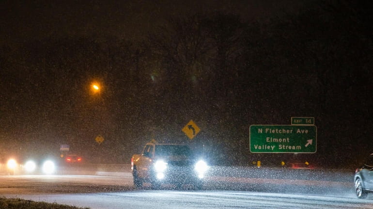 Snowfall coats the road surface of the Southern State Parkway...