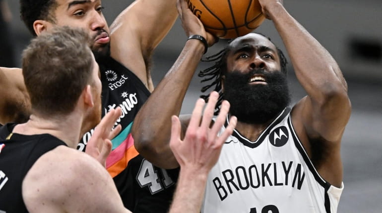 The Nets' James Harden attempts to shoot as he is defended...
