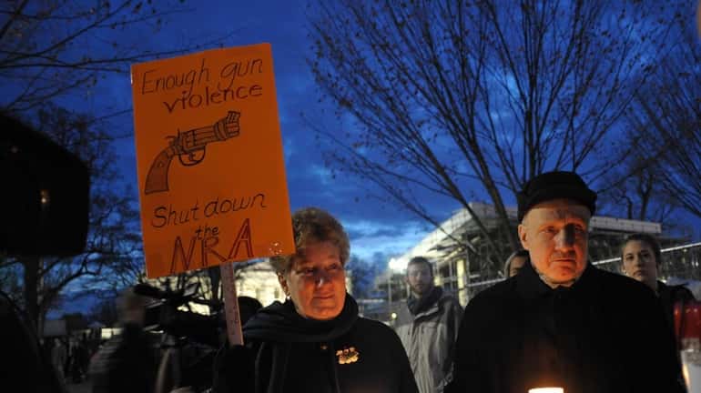 Gun control supporters take part in a candlelight vigil at...