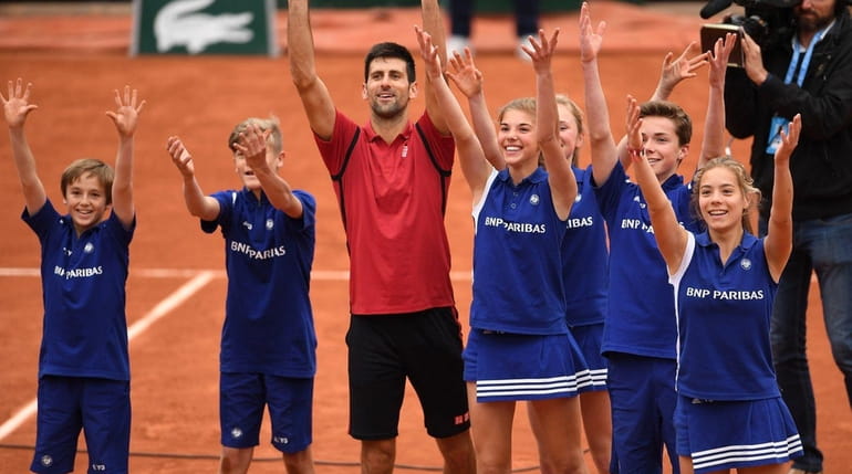 Novak Djokovic celebrates victory with the ballkids during the men's...