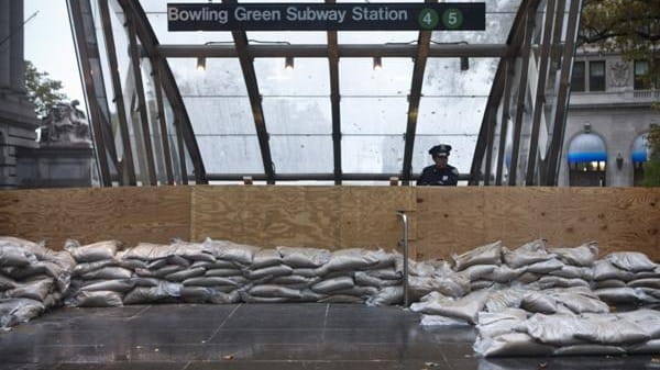 A police officer stands behind a barricaded subway entrance near...