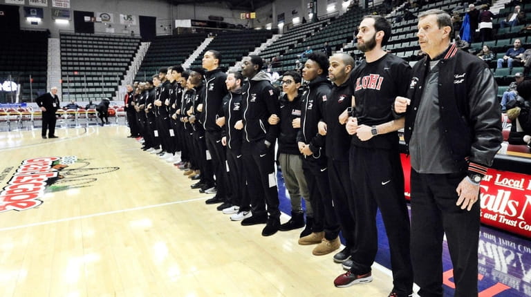 Long Island Lutheran players and coaching staff stand in silent...