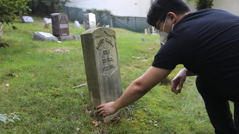 Stony Brook graduate Gary Ghayrat, visits the grave of David Carll,...