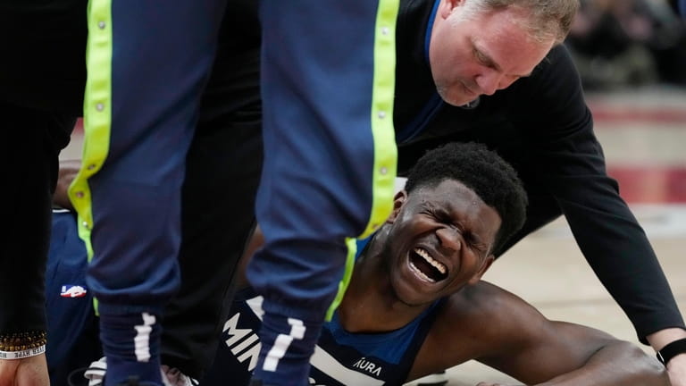 Minnesota Timberwolves guard Anthony Edwards reacts after an apparent injury...