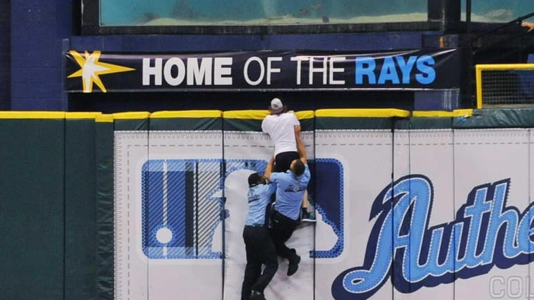 Security chases a fan of the Tampa Bay Rays as...