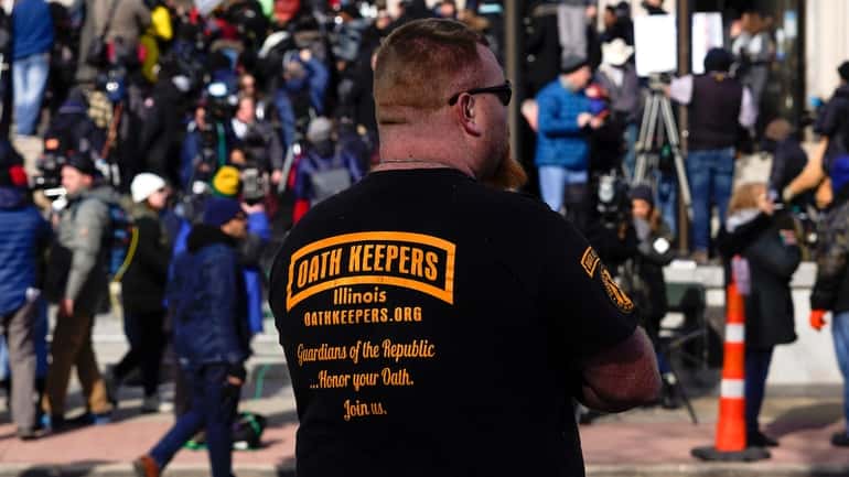 A man wearing an Oath Keepers shirt stands outside the...