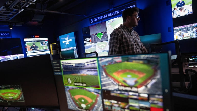 An employee walks past screens displaying gameplay clips at a...