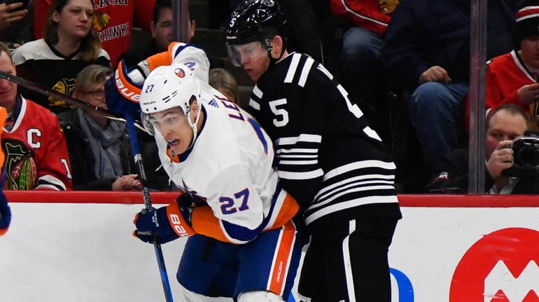 Islanders lineman Anders Lee fights for the puck against Chicago...