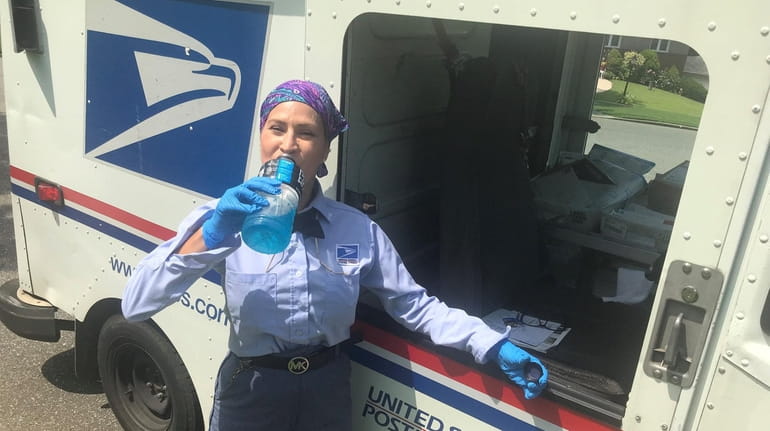 U.S. Postal Service worker Moraima Lopez pauses to cool off while delivering mail Friday...