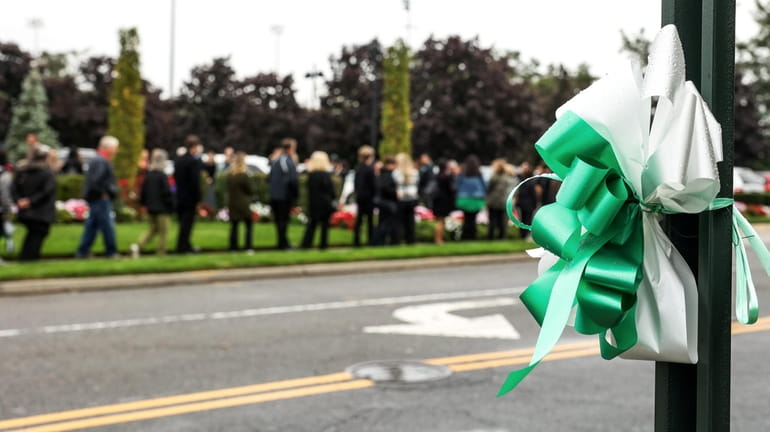 Green and white ribbons are attached to a pole across...