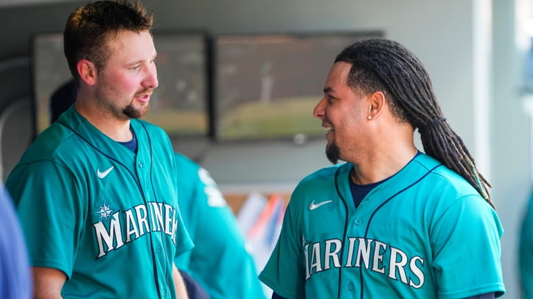 Seattle Mariners' Cal Raleigh, left, talks with starting pitcher Luis...
