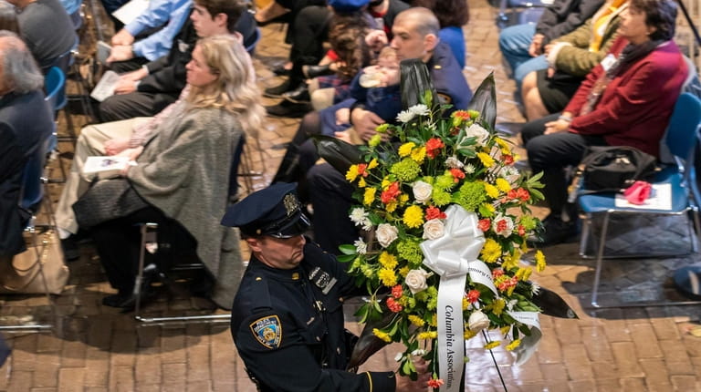 A police officer places flowers at a memorial service for...