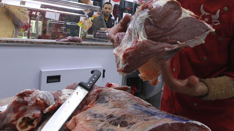 Workers prepare meat to be sold to customers in a...