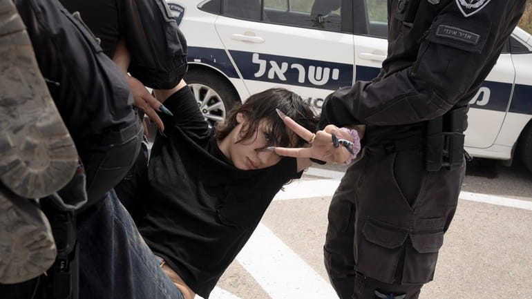 A protester gestures as she is carried to a police...