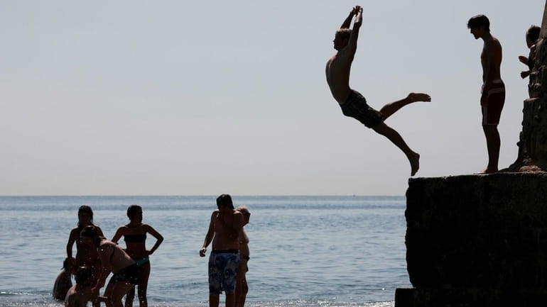 Swimmers jump into the sea from a pier on Brighton...