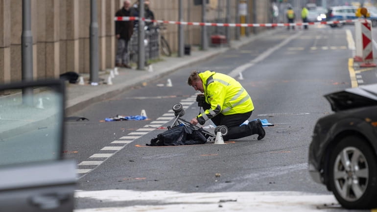 A police officer kneels on a stroller at the scene...