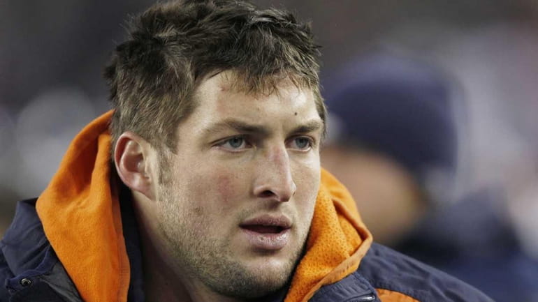 Denver Broncos quarterback Tim Tebow watches from the sidelines during...