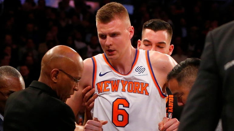Knicks forward Kristaps Porzingis is helped off the court after...