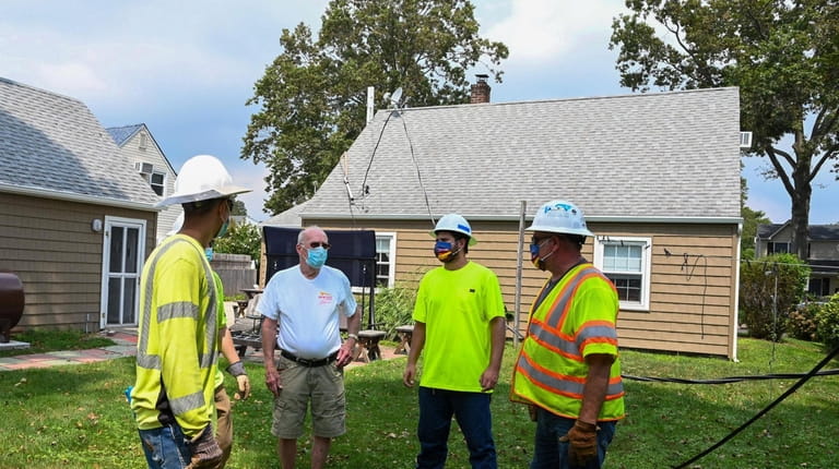 Homeowner Alex Chisholm talks to ulility electrical workers from River City...