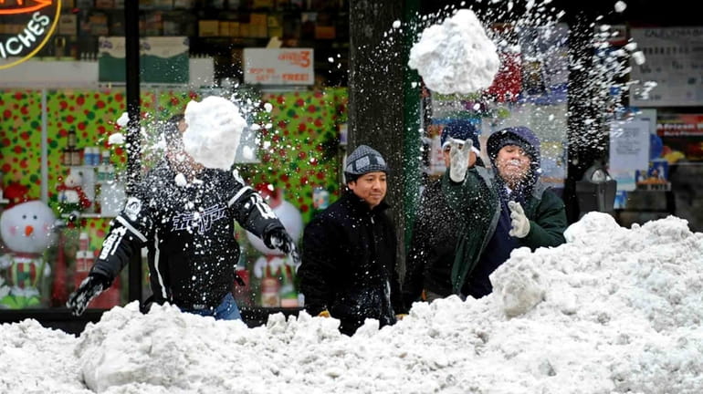 Men try to clear a pile of snow on Third...
