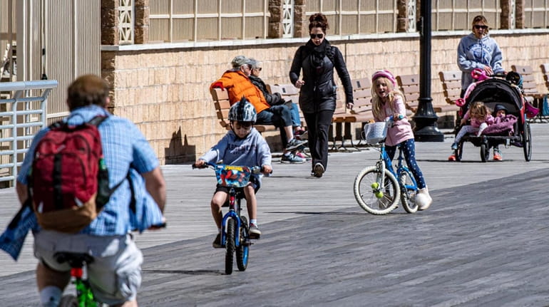 People walk and ride bikes along the boardwalk in Long Beach on...
