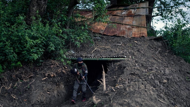 An armed tribal Kuki walks out of an underground bunker...