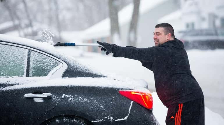 Chris Voccola clears ice and snow from his car on...