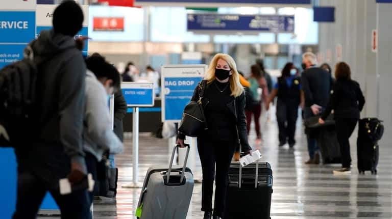 A traveler wore a mask as she walked Sunday through Terminal 3...