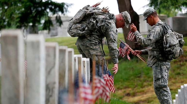 Members of the 3rd U.S. Infantry Regiment place American flags...